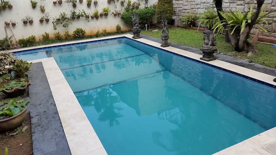 Kolam renang outdoor dengan border keramik putih dan taman